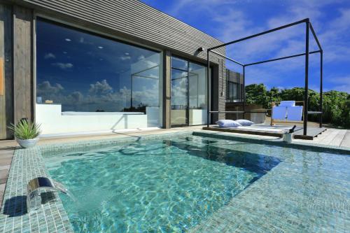 a swimming pool in front of a house at 鸛巣（ムカカヴィラ コウノス) in Nakijin
