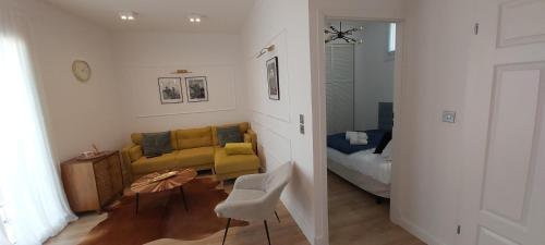 ein Wohnzimmer mit einem gelben Sofa und einem Bett in der Unterkunft 123 Sadi Carnot, classé 2 étoiles in Saint-Raphaël