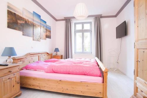 een slaapkamer met een houten bed met roze lakens bij Wohnung Eule im Haus Seeadler in Zinnowitz