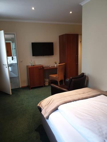 a hotel room with a bed and a desk and a television at Hotel Knipper in Lastrup