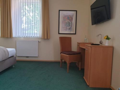 a hotel room with a bed and a desk and a television at Hotel Knipper in Lastrup
