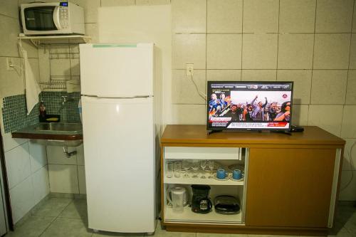 einen Kühlschrank in einer Küche mit einem TV in der Unterkunft Suíte Abreu Noronha in Fernando de Noronha