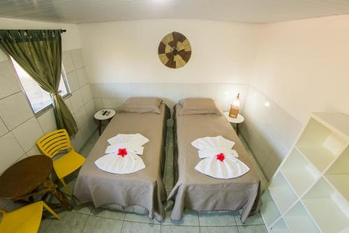 2 Betten in einem kleinen Zimmer mit einer Uhr an der Wand in der Unterkunft Suíte Abreu Noronha in Fernando de Noronha