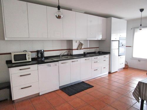 a kitchen with white cabinets and a sink and a microwave at The Artist´s Apartment in Espinho