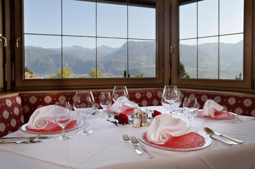 a table with red and white plates and wine glasses at Hotel Mühle Mayer in Termeno
