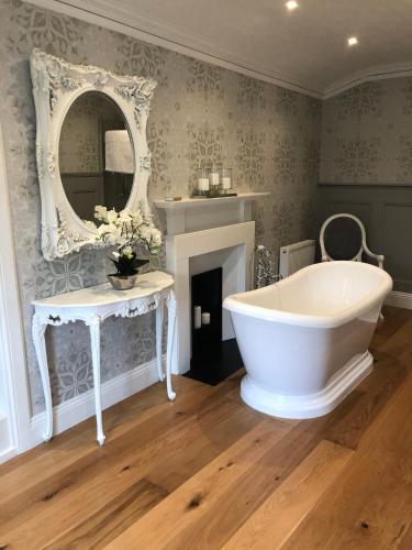 a bathroom with a white tub and a mirror at Branxholme Castle (Bed & Breakfast) in Hawick