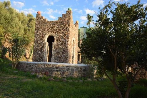 an old stone building with an arch in a field at Hotel Leonor in Had Beni Chiker