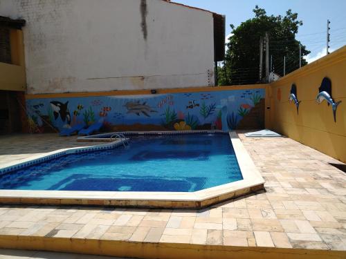 a swimming pool in front of a building with a mural at Cantinho da Felicidade in Praia do Frances