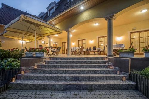 a set of stairs in front of a house with an umbrella at Regia Panzió in Halászi