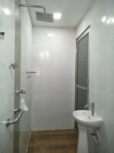 a white bathroom with a sink and a shower at Zainab Cottage in Pasir Puteh