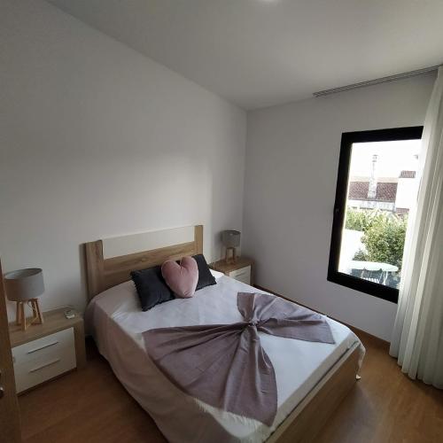 um quarto com uma cama com uma almofada cor-de-rosa e uma janela em Helena's House em Ponta Delgada