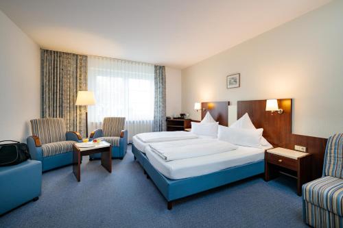 a hotel room with a bed and two chairs at Hotel Seeschwalbe in Cuxhaven