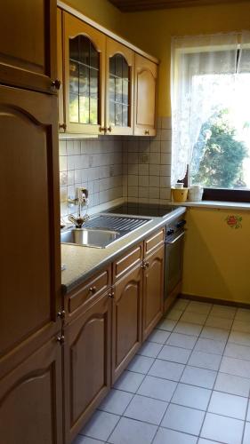 a kitchen with wooden cabinets and a sink and a window at Ferien Penthouse Panoramablick oder Studio Panoramablick in Bad Grund