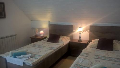 two beds in a small room with two lamps at Apartment & Rooms Miboti in Samobor