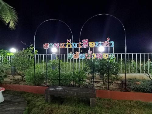 a fence with neon signs on it at night at บ้านสวนแก้วเฮือนคำ in San Pa Tong
