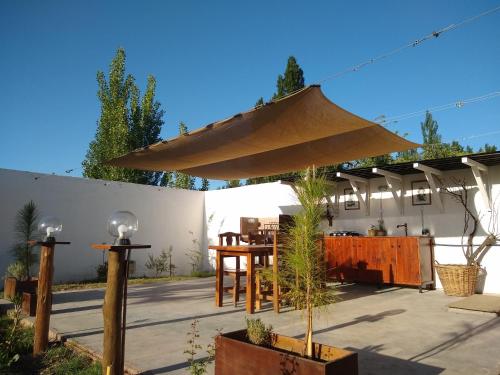 a patio with a table and a large umbrella at Finca La Penúltima-Posada in San Rafael