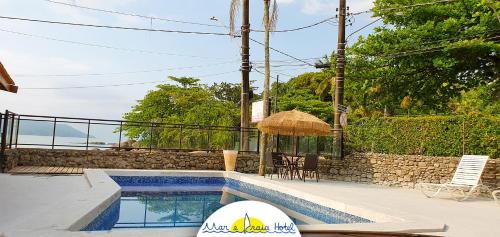 una piscina con sombrilla junto a una casa en Mar e Praia Hotel, en Ubatuba
