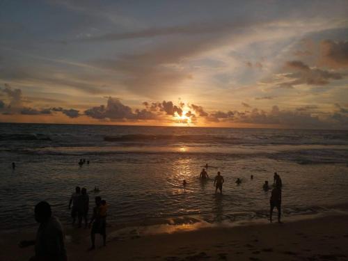 a group of people on the beach at sunset at Akurala Beach Park in Hikkaduwa