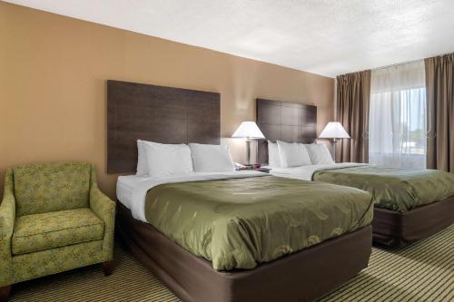 a hotel room with two beds and a chair at Quality Inn McDonough Atlanta South in McDonough