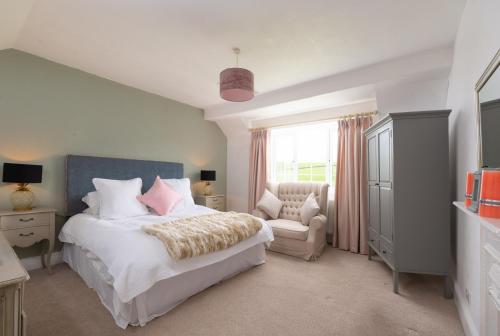 a bedroom with a bed and a chair and a window at Braunton Farmhouse in Braunton