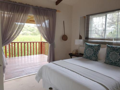 a bedroom with a large bed and a balcony at WOODPECKER in Plettenberg Bay