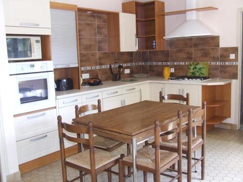 cocina con mesa de madera y sillas en Gite à la ferme Les places en La Chapelle-Bertrand