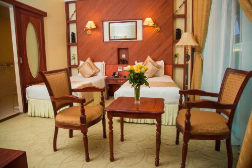 a hotel room with two beds and a table with flowers at Palace Hotel Arusha in Arusha