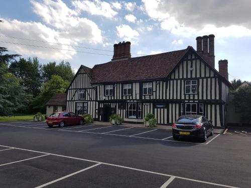 a black and white building with two cars parked in a parking lot at The White Hart in Great Yeldham