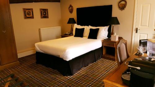 um quarto de hotel com uma cama e uma secretária em The White Hart em Great Yeldham