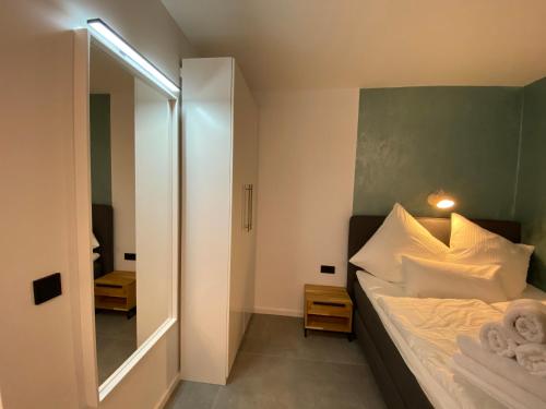 a bedroom with a bed with white pillows and a mirror at City Apartments Hannover in Hannover