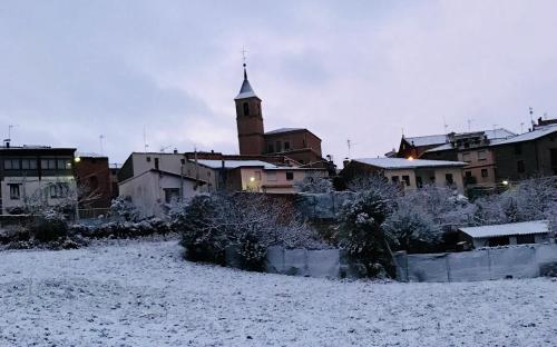 a snow covered city with a clock tower in the background at Casa Rural Nestazar II in Berceo