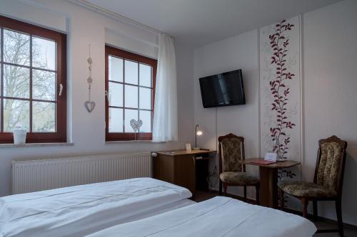 a bedroom with a bed and two chairs and a desk at Hotel & Restaurant Lindengarten in Lübben