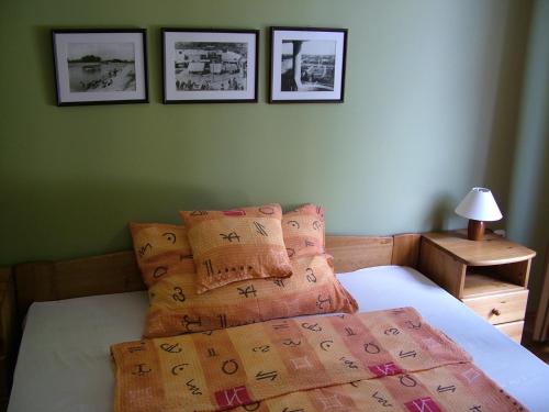 a bedroom with a bed with four pictures on the wall at Gimi Vendégház in Baja