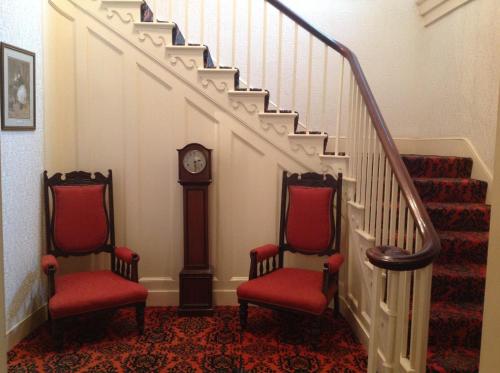 a staircase with two chairs and a grandfather clock at The Gro Guest house in Newtown