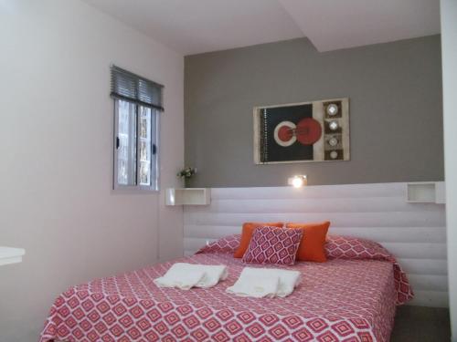 a bedroom with a large bed with orange pillows at Dandy Suites in Mar de las Pampas