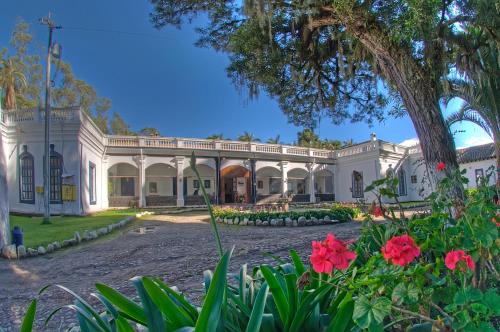 a large white mansion with flowers in the foreground at Hostería Hacienda Pinsaqui in Otavalo