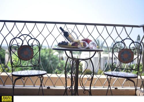 two chairs and a table with a plate of food on a balcony at Royal Suite Caesarea in Caesarea