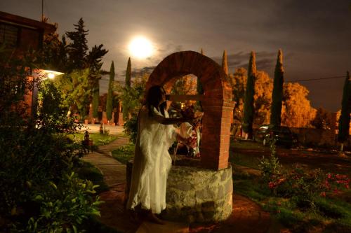a woman in a white dress standing next to a brick wall at Hotel Casa de la Luna in San Juan Teotihuacán