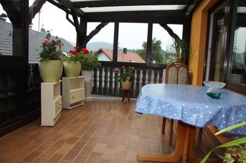 eine abgeschirmte Veranda mit einem Tisch und Blumen in der Unterkunft Gästehaus Alexanna in Baden-Baden