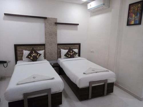 2 aparte bedden in een kamer met witte muren bij Hotel Park Residency in Vijayawāda
