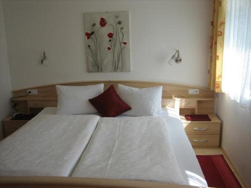 łóżko z białą pościelą i czerwonymi poduszkami w sypialni w obiekcie Ferienwohnungen Pötscher Maria w mieście Matrei in Osttirol