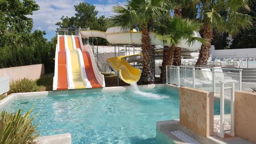une piscine avec un toboggan aquatique dans un complexe hôtelier dans l'établissement Mobile Home tout confort Séléna, à Agde