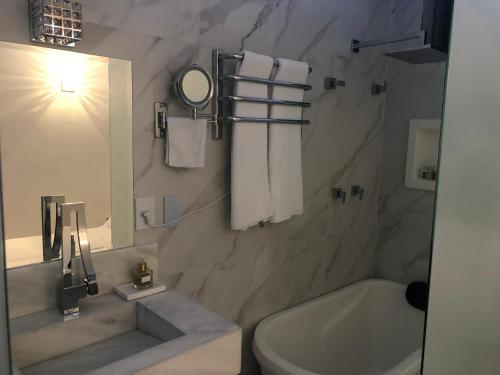 a bathroom with a sink and a toilet and a tub at Apart Hotel Delphin Guaruja in Guarujá