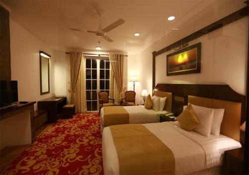 a hotel room with two beds and a television at The Blackpool Resort & Spa in Nuwara Eliya