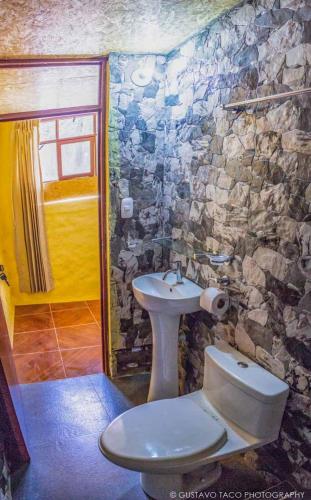 a stone bathroom with a toilet and a sink at Paraiso Las Palmeras Lodge in Cabanaconde