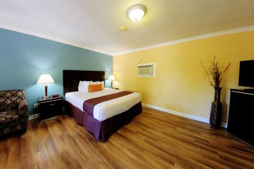 a hotel room with a bed and a chair at Palm Tropics Motel in Glendora