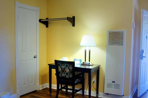 Cette chambre comprend un bureau avec une lampe et une chaise. dans l'établissement Palm Tropics Motel, à Glendora