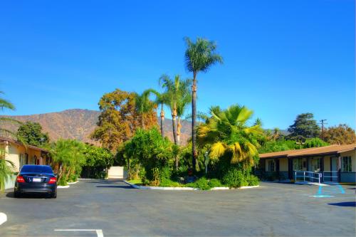 a car parked in a parking lot with palm trees at Palm Tropics Motel in Glendora