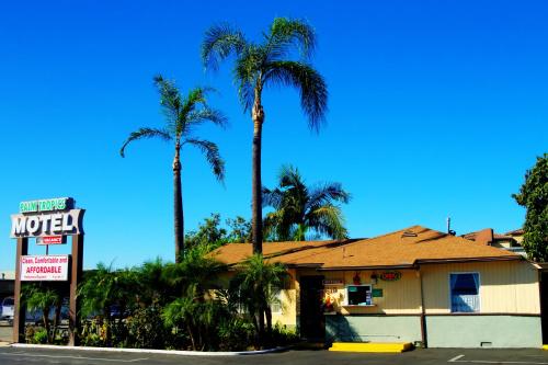 a motel with palm trees in front of a building at Palm Tropics Motel in Glendora