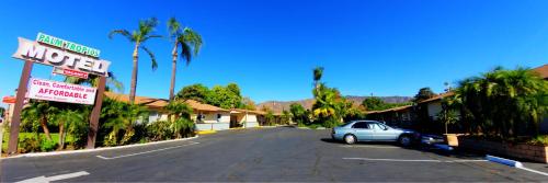 a car parked in a parking lot next to a motel at Palm Tropics Motel in Glendora